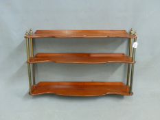 A SET OF VINTAGE MAHOGANY AND BRASS THREE TIER HANGING SHELVES OF SERPENTINE FORM, H. 58 X W. (OPEN)