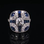 A PLATINUM SAPPHIRE AND DIAMOND ART DECO DESIGN RING. THE CENTRAL OLD CUT DIAMOND SURROUNDED BY BLUE