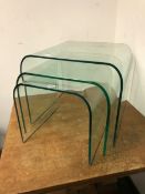 A NEST OF THREE RETRO CURVED GLASS TABLES OF GRADUATED SIZE. LARGEST, H. 45 x W. 55 x D. 50cms.