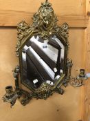 A BRASS FRAMED GIRANDOLE MIRROR CRESTED BY A MASK OF A LADY AMONGST FOLIAGE, THE CANTED