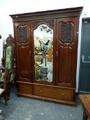 AN EDWARDIAN MAHOGANY WARDROBE, THE CENTRAL SERPENTINE TOPPED BEVELLED GLASS MIRROR FLANKED BY DOORS