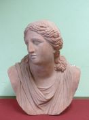 A SLIP CAST TERRACOTTA BUST OF A CLASSICAL LADY, HER LONG HAIR TIED WITH A RIBBON ABOVE HER