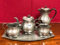 A ROUNDHEAD PEWTER FOUR PIECE TEA SET ON A TRAY, EACH WITH HAMMERED DECORATION, THE TRAY. W 41cms.