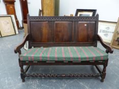 AN ANTIQUE AND LATER OAK CARVED PANEL BACK SETTLE. TURNED SUPPORTS WITH BARLEY TWIST FRONT