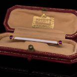 A CARTIER 14ct GOLD WHITE ENAMEL AND CABOCHON RUBY BAR BROOCH IN A CARTIER FITTED CASE. SIGNED
