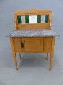 AN EDWARDIAN GREY MARBLE TOPPED PINE WASHSTAND WITH A TILED BACK ABOVE A DOOR TO THE FRONT, THE