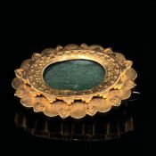 A 15ct GOLD OVAL PANEL BROOCH. A FLARED BORDER WITH A HEART DESIGN FRAMES A GLAZED PERSPEX PANEL