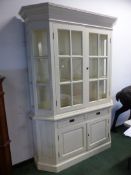 A WHITE PAINTED COUNTRY STYLE DISPLAY CABINET, THE GLAZED DOORS ABOVE TWO DRAWERS AND TWO PANELLED