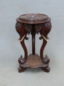 AN ANTIQUE CARVED HARDWOOD EASTERN URN STAND WITH ELEPHANT HEAD SUPPORTS. Dia. 48cm x H. 80cm.