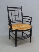 A WILLIAM MORRIS EBONISED RUSH SEATED ELBOW CHAIR TO A DESIGN BY FORD MADDOX BROWN, THE ROUNDED ARMS
