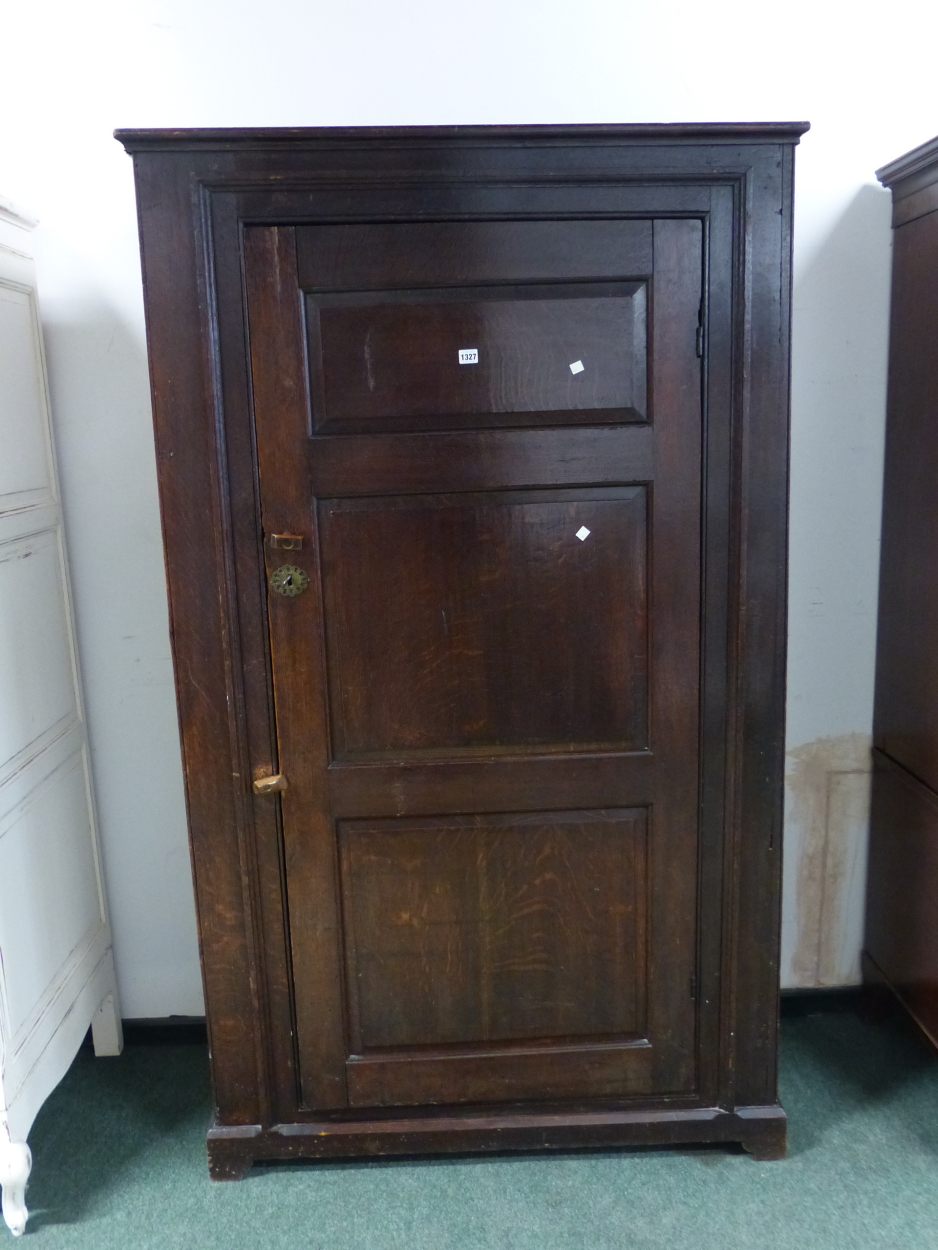 AN 18th C. OAK CUPBOARD WITH THE THREE PANELLED DOOR ENCLOSING HANGING SPACE ABOVE A SHELF AND THE