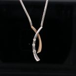 A 9ct GOLD AND DIAMOND "X" NECKLACE. THE TWO COLOUR PENDANT SET WITH THREE GRADUATED BRILLIANT CUT