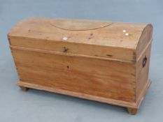 A PINE COFFER WITH ROUND ARCHED LID AND RECTANGULAR SIDES TAPERING TO A PLINTH AND THE STILE FEET,