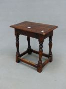 AN OAK JOINT STOOL WITH THE RECTANGULAR TOP ON BALUSTER LEGS JOINED BY STRETCHERS AT THE SQUARE