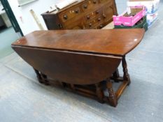 AN OAK WAKE TABLE, THE OVAL DROP FLAP TOP ON BALUSTER TURNED LEGS JOINED BY STRETCHERS ABOVE THE