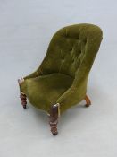 A GREEN VELVET BUTTON BACKED VICTORIAN CHAIR ON MAHOGANY FRONT LEGS CARVED WITH CABOCHONS AND ON