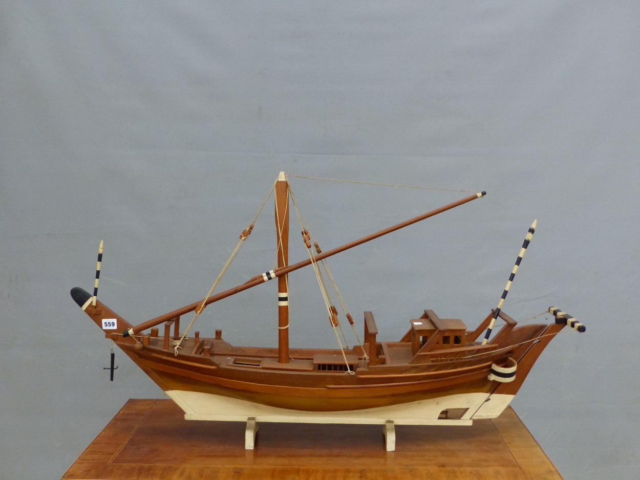 A SCALE MODEL TEAK DHOW WITH WHITE PAINTED KEEL AND BLACK AND WHITE TILLER HANDLE. W 105cms.