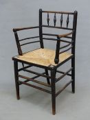 A WILLIAM MORRIS EBONISED WOOD SUSSEX CHAIR WITH FOUR VERTICAL SPINDLES BELOW THE TOP RAIL, THE RUSH