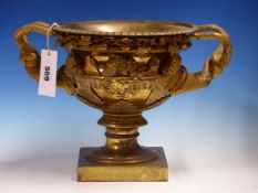 A GILT BRONZE WARWICK URN, THE TWO TWISTED VINE HANDLES FLANKED BY APPLIED MASKS ABOVE THE SOCLE AND