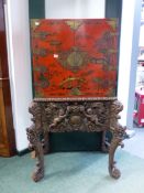 A RED LACQUER CHINOISERIE CABINET ON A BAROQUE STYLE STAND PIERCED AND CARVED WITH FOLIAGE ABOUT TWO