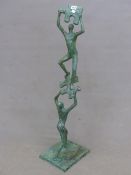 A GREEN PATINATED BRONZE GROUP OF TWO FIGURES, ONE HOLDING UP A JIGSAW PIECE ON WHICH THE SECOND