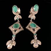 A PAIR OF EMERALD AND DIAMOND ARTICULATED EDWARDIAN STYLE DROP EARRINGS SET IN CONTINENTAL SILVER.