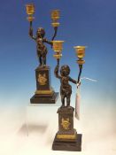 A PAIR OF PARCEL GILT BRONZE CANDLESTICKS, EACH WITH TWO GILT CANDLE HOLDERS HELD UP BY PUTTI