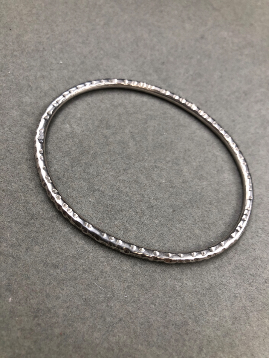 A SOLID SILVER HAMMERED FINISHED OVAL BANGLE, DATED 1988. WEIGHT 16.2grms.