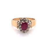 A 9ct HALLMARKED GOLD RUBY AND DIAMOND CLUSTER RING. THE CENTRAL OVAL CUT RUBY IN A TEN CLAW