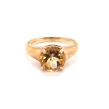 A 9ct HALLMARKED YELLOW GOLD SINGLE STONE ORANGE GEMSET RING. THE BRILLIANT CUT GEMSTONE IN A FOUR