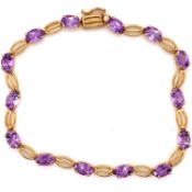 A 9ct HALLMARKED GOLD AND AMETHYST BRACELET. THE FOURTEEN OVAL FACET CUT AMETHYSTS EACH IN A FOUR