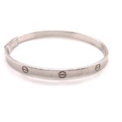 A LOVE BANGLE WITH ENGRAVED SCREW HEAD DESIGN AND A HINGED OPENING. STAMPED 375 AND ASSESSED AS