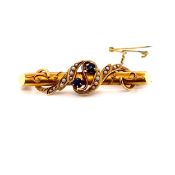 AN ANTIQUE 15ct STAMPED YELLOW GOLD SAPPHIRE AND SEED PEARL BAR BROOCH WITH APPLIED SCROLL DESIGN