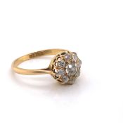 AN ANTIQUE OLD CUT DIAMOND AND 18ct STAMPED DAISY CLUSTER RING. THE OLD CUT DIAMONDS IN DROPPED CLAW