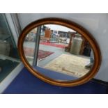 AN OVAL GILT FRAME WALL MIRROR.