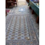 AN ORIENTAL RUG OF BOKHARA DESIGN 241 X 169 T/W TWO MACHINE MADE RUGS , ONE A PRAYER RUG AND THE