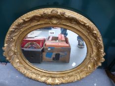 A GILT FRAMED OVAL MIRROR.