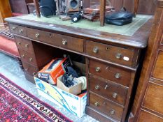 A GREEN LEATHER INSET OAK KNEEHOLE DESK WITH NINE DRAWERS