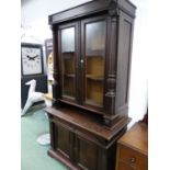 AN OAK DISPLAY CABINET, THE UPPER HALF WITH GLAZED DOORS BETWEEN COLUMNS. W 114 x D 57 x H 209cms.