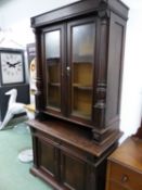 AN OAK DISPLAY CABINET, THE UPPER HALF WITH GLAZED DOORS BETWEEN COLUMNS. W 114 x D 57 x H 209cms.