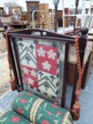 A VINTAGE GLAZED FIRESCREEN HUNG WITH EMBROIDERED ARMORIAL BANNER.