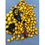 TWO COMPLETE STRANDS OF GRADUATED AMBER BEADS, TOGETHER WITH A QUANTITY OF LOOSE AMBER BEADS, AND