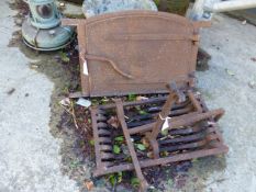 A CAST IRON FIRE BASKET WITH DOGS AND A SMALL CAST IRON DOOR.