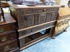 AN OAK SIDEBOARD, THE TWO DOORS BETWEEN TWO LONG DRAWERS EACH CARVED IN RELIEF WITH FOLIAGE