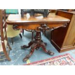 A VICTORIAN ROSEWOOD SWIVEL TOPPED GAMES TABLE ON GADROONED COLUMN AND FOUR FOLIATE CARVED FEET