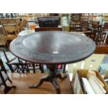 AN OAK TRIPOD TABLE WITH A LEAF BAND CARVED INTO THE CIRCULAR TOP