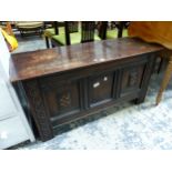 AN OAK THREE PANEL FRONTED COFFER INLAID WITH TWO CHEQUER SHIELDS