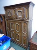 A GERMANIC FAUX BOIS PAINTED CABINET WITH TWO DOORS ABOVE A TALLER DOOR BETWEEN PANELS PAINTED