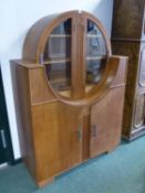 AN ART DECO OAK SIDE CABINET WITH A CIRCLE OF GLAZED DOORS OVER SHELVES ABOVE AND BETWEEN