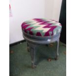 A GREEN PAINTED METAL FOUR LEGGED STOOL ON CASTER FEET, THE ROUND SEAT UPHOLSTERED